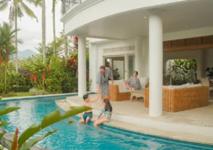 Family relaxing at private pool villa in Ubud surrounded by tropical gardens and rice field scenery