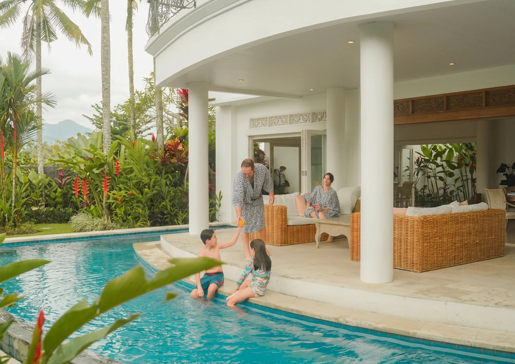 Family relaxing at private pool villa in Ubud surrounded by tropical gardens and rice field scenery