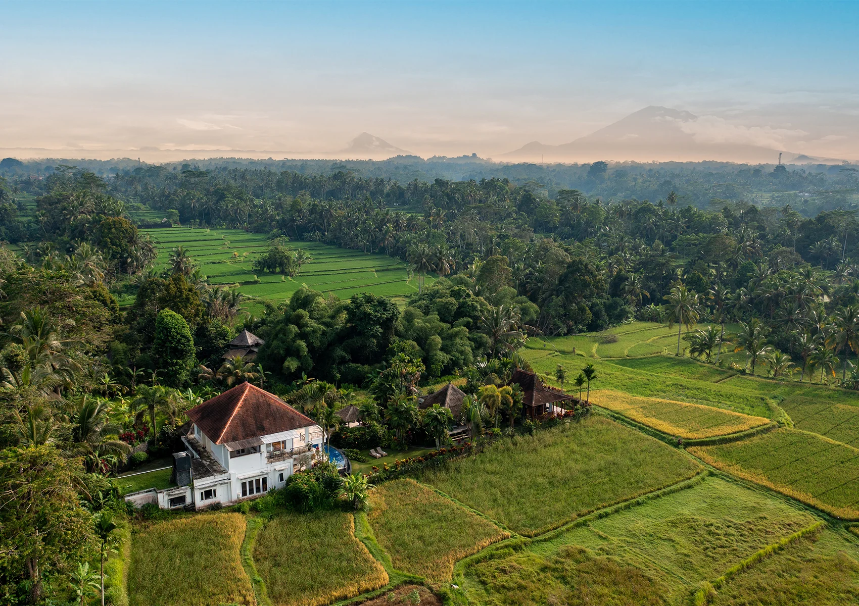 Staying at a Family Villa Near Tegallalang Rice Terraces in Ubud Aerial view of a family villa surrounded by Tegallalang rice terraces in Ubud, Bali, with lush tropical landscapes and mountain scenery.