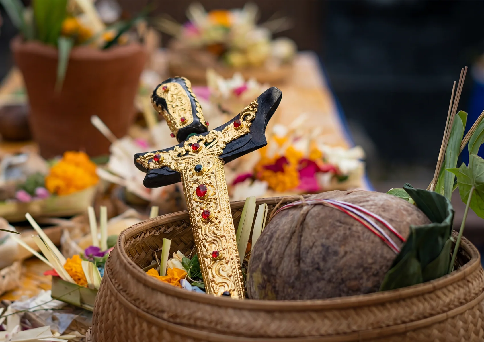 Traditional Balinese ceremonial offerings with flowers, coconut, incense, and sacred kris dagger prepared for a Hindu ritual in Bali